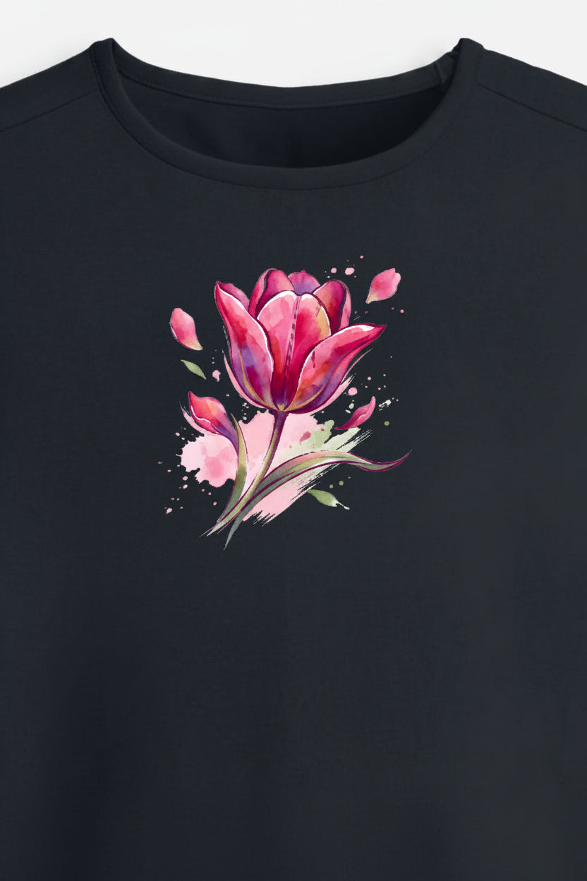 A black short-sleeve crop top t-shirt featuring a vibrant pink watercolor tulip graphic on the center chest, displayed against a light gray background.